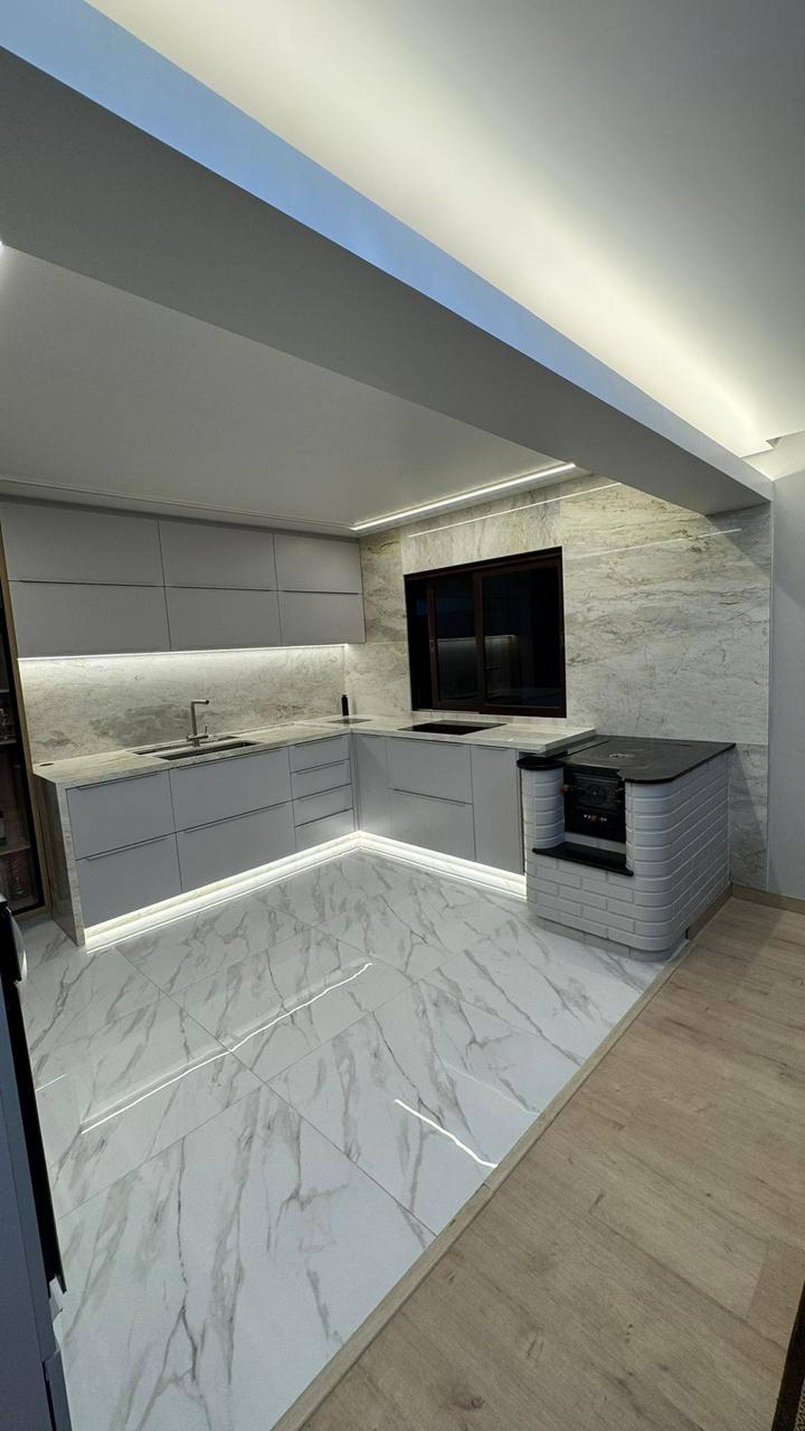 Detalhe de cozinha em mármore branco Paraná com cuba esculpida e frontão contínuo.